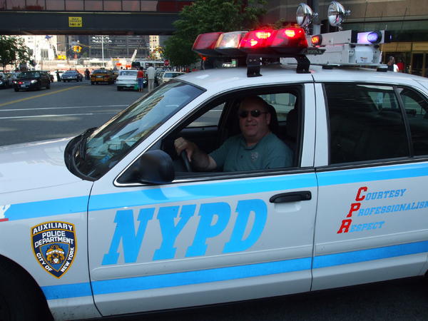 A photo of me sitting in an NYPD cruiser with Ground Zero in the background during NYPD musuem car show 2008. Approximately 40 to 50 vintage cars were